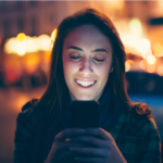 Young woman using an iPhone in an evening city setting.